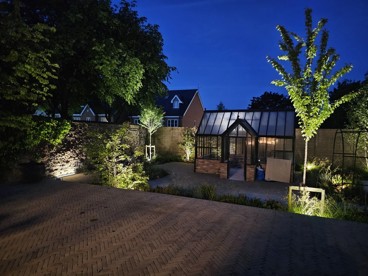 Garden planting and a greenhouse lit at dusk