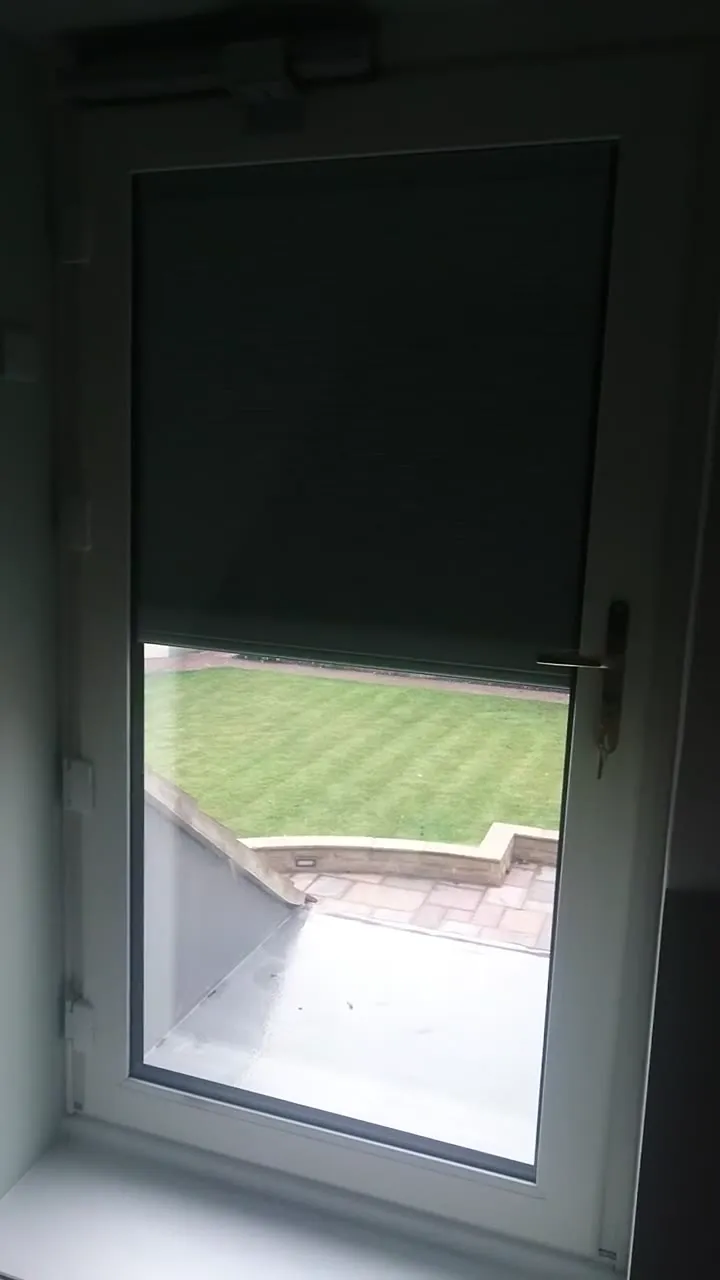 A pleated blackout blind inside the glass of a bedroom door