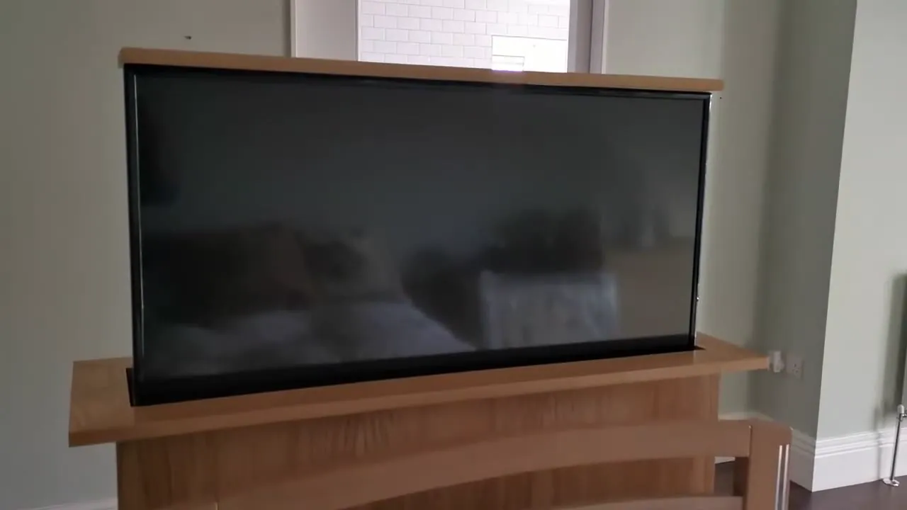 A bedroom TV raised out of its oak cabinet